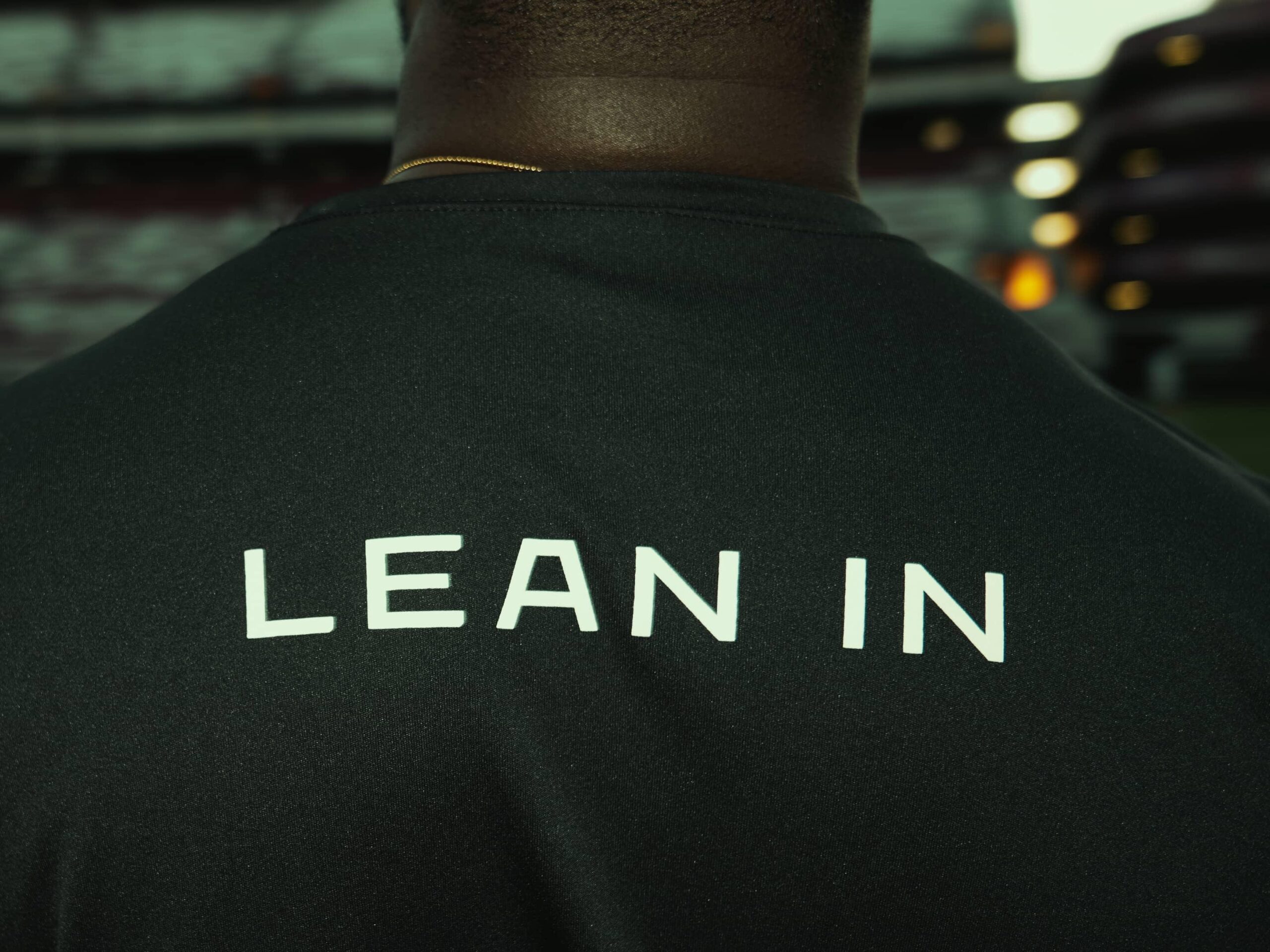 Athlete seen from behind in a stadium, wearing a shirt that reads Lean In